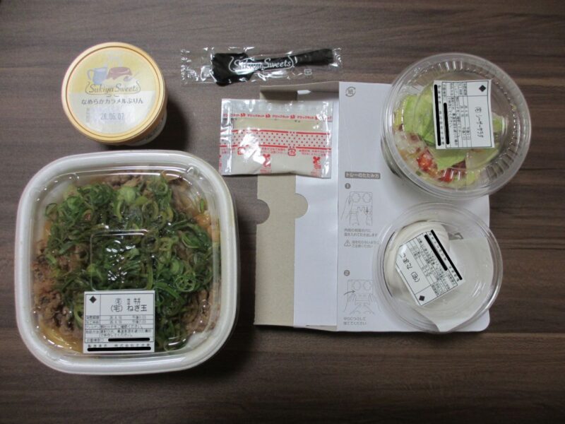 袋から取り出した、フタが閉まった状態の牛丼やサラダ、卵、プリン